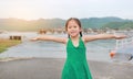 Smiling Asian child girl opened her hands and relaxes in hillside