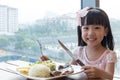 Smiling Asian Chinese little girl eating lamb steak with rice