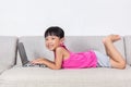 Smiling Asian Chinese little girl laying on sofa using laptop Royalty Free Stock Photo