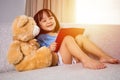 Smiling Asian Chinese little girl reading book with teddy bear Royalty Free Stock Photo