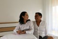 Smiling Asian couple sitting on the bed together