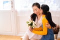 Smiling Asian daughter hugging and kissing her mother in living room at home Royalty Free Stock Photo