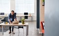 Smiling Asian designer leaning on his desk using a laptop Royalty Free Stock Photo