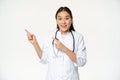 Smiling asian doctor, female healthcare worker pointing at upper left corner, looking amazed, showing medical Royalty Free Stock Photo