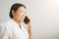 Smiling Asian elderly woman while talking on mobile phone showing happy mood Royalty Free Stock Photo