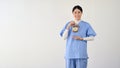 A smiling Asian female doctor in scrubs holds a vintage alarm clock. punctual, right timing