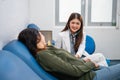 smiling Asian female doctor using a stethoscope while examining a patient Royalty Free Stock Photo