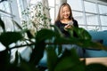 Smiling asian female IT employee using smartphone on sofa in coworking office Royalty Free Stock Photo