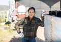 Smiling asian female farmer standing outdoors leaning on farm truck