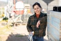 Smiling asian female farmer standing outdoors leaning on farm truck