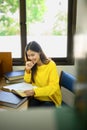Smiling asian female student reading book, doing class assignment. in library. Education, learning and people concept Royalty Free Stock Photo