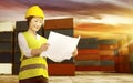 Smiling asian female worker with safety vest and hard hat holding blueprint on the dock