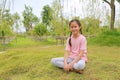 Smiling Asian girl child looking camera while sitting on lawn in the garden Royalty Free Stock Photo