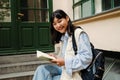 Smiling asian girl holding textbook while sitting outdoors Royalty Free Stock Photo