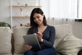 Smiling Asian girl relax on sofa using tablet gadget Royalty Free Stock Photo