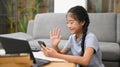 Smiling asian girl sitting on floor in living room and using mobile phone during learning online. Concept of Virtual Royalty Free Stock Photo