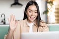 Smiling asian girl student waving hand at laptop camera. Woman on video call from home, saying hello on videochat Royalty Free Stock Photo