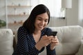 Smiling Asian girl use modern smartphone at home Royalty Free Stock Photo