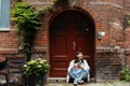 Smiling asian girl using mobile phone and drinking coffee while sitting outdoors Royalty Free Stock Photo