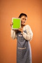 smiling Asian girl wearing apron showing blank digital tablet