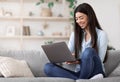 Smiling Asian Girl Working Remotely On Laptop At Home, Sitting On Couch Royalty Free Stock Photo