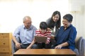 Smiling Asian grandparents on couch with granddaughter looking at tablet. Royalty Free Stock Photo