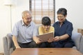 Smiling Asian grandparents on couch with granddaughter looking at tablet. happy three generation family spending time together at Royalty Free Stock Photo