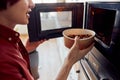 Smiling Asian guy placing a plate of food in the microwave Royalty Free Stock Photo