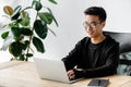 smiling asian hacker in glasses sitting