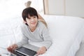 Smiling Asian little boy is studying and doing homework with laptop  in bedroom. Homeschool and quarantine during Covid-19 virus Royalty Free Stock Photo