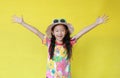 Smiling asian little child girl with closed eyes wearing a floral pattern summer dress and hat with sunglasses isolated on yellow Royalty Free Stock Photo