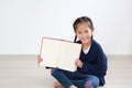 Smiling asian little child girl open book. Caucasian kid sitting in room and holding blank page of book Royalty Free Stock Photo