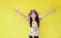 Smiling asian little child girl wearing a floral pattern summer dress and hat with sunglasses isolated on yellow background. Royalty Free Stock Photo
