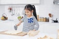 Smiling Asian little asian girl child is learning and enjoying for baking cookies bakery on wooden Cutting board in kitchen. Royalty Free Stock Photo