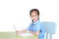 Smiling Asian little girl in school uniform writing on notebook at desk isolated on white background. Schoolgirl and Education Royalty Free Stock Photo
