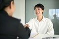 Smiling Asian male candidate shaking hands with a businesswoman after a job interview Royalty Free Stock Photo