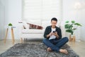 Smiling asian man happy wearing casual clothes t-shirt sitting on a couch sofa or floor at the living room at home. Asian man Royalty Free Stock Photo