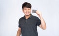 Smiling Asian man holding black credit card, look at camera, studio light portrait isolated on white background Royalty Free Stock Photo