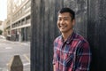 Smiling Asian man leaning against a wall in the city Royalty Free Stock Photo