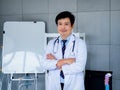 Smiling Asian man orthopedic doctor portrait in white coat standing with crossed arms near white board in medical office. Royalty Free Stock Photo