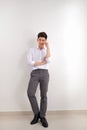 Smiling Asian man in pants and shirt standing near blank wall. Concept of businessman. Mock up Royalty Free Stock Photo