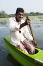 Smiling Asian man row a small traditional boat