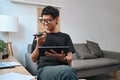 Smiling asian man talking on mobile phone and using digital tablet at home. Royalty Free Stock Photo