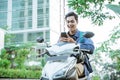 Smiling asian man using a cellphone while riding a motorcycle Royalty Free Stock Photo