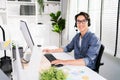 A smiling Asian man working as customer support operator with a headset in a call center. Portrait of sales agent sitting at desk Royalty Free Stock Photo