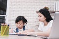 Smiling Asian mother and little girl child is drawing and Painting with wooden colored pencils on paper together in worksapce area Royalty Free Stock Photo