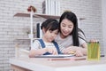 Smiling Asian mother and little girl child is drawing and Painting with wooden colored pencils on paper together in worksapce area Royalty Free Stock Photo