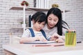 Smiling Asian mother and little girl child is drawing and Painting with wooden colored pencils on paper together in worksapce area Royalty Free Stock Photo