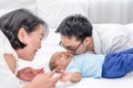 Smiling Asian mother looking at her husband kissing 5 months baby boys son in bedroom Royalty Free Stock Photo