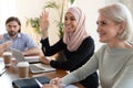 Smiling Asian muslim businesswoman raising hand, asking question at meeting Royalty Free Stock Photo